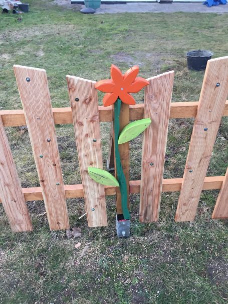 Zaun aus Lärche Bunte Holzblume an einem Holzzaun mit grünen Blättern.